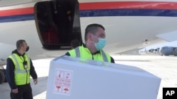 In this photo provided by the Serbian Presidential Press Service, a worker holds a box of the Astra-Zeneca vaccines at Sarajevo Airport, Bosnia, March 2. 2021.