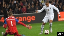 FILE - France's forward Kylian Mbappe (R) vies with Iceland's goalkeeper Hannes Thor Halldorsson during a friendly football match between France and Iceland at the Roudourou Stadium in Guingamp, western France, Oct. 11, 2018.