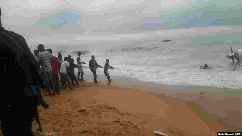 Des riverains aident à tirer l’épave d’avion abîmée au bord de la mer au Port Bouet, au large d’Abidjan, Côte d’ivoire, 14 octobre 2017. (VOA/Narita Namasté)