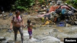 Una migrante camina junto a una niña en Acandi, Colombia, mientras continúan su camino a Estados Unidos, el 9 de Julio de 2023. Este año, siguen creciendo las cifras récord de migración a través del Tapón del Darién, que conecta a Colombia y Panamá.