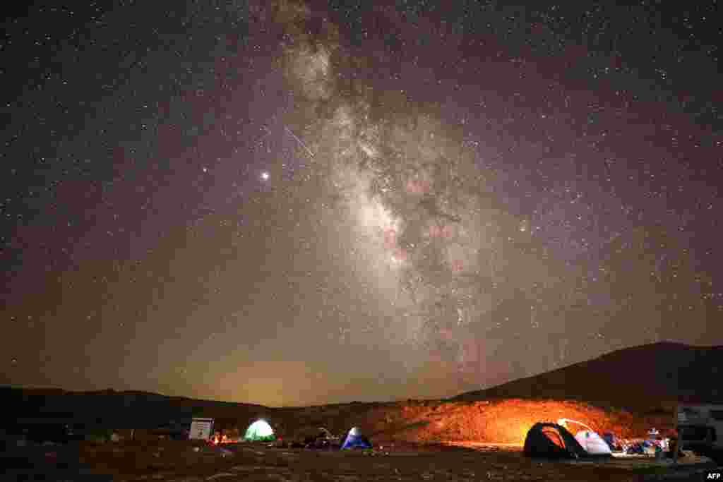 A Perseid meteor streaks across the sky above a camping site at the Negev desert near the city of Mitzpe Ramon, Israel, during the Perseids meteor shower, Aug. 11, 2020,