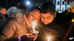 ARCHIVO - Personas sostienen velas durante una vigilia con velas el 17 de diciembre de 2024, afuera del Capitolio de Wisconsin en Madison, Wisconsin, luego de un tiroteo en la Escuela Cristiana Abundant Life. 