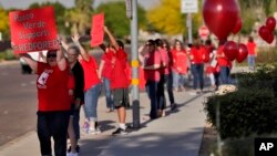 Teachers and students wave to motorists outside Paseo Verde Elementary, April 18, 2018, in Peoria, Ariz. 