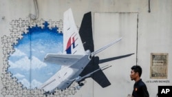 Seorang pria tengah berjalan melintasi lukisan mural dari pesawat Malaysia Ailines MH370 di Shah Alam, luar kota Kuala Lumpur, Malaysia. (Foto:AP Photo/Joshua Paul)