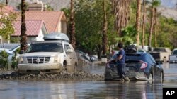 Dorian Padilla permanece de pie cerca de su automóvil mientras espera un remolque después de que se atascó en el barro en una calle mientras otro vehículo pasaba. Visto el lunes 21 de agosto de 2023 en Cathedral City, California, EEUU.