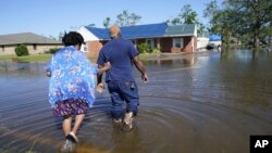 Sonya i Patrick King prolaze poplavljenom ulicom do svoje kuće u Lake Charlesu, (Foto: AP Gerald Herbert)