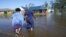 Sonya i Patrick King prolaze poplavljenom ulicom do svoje kuće u Lake Charlesu, (Foto: AP Gerald Herbert)