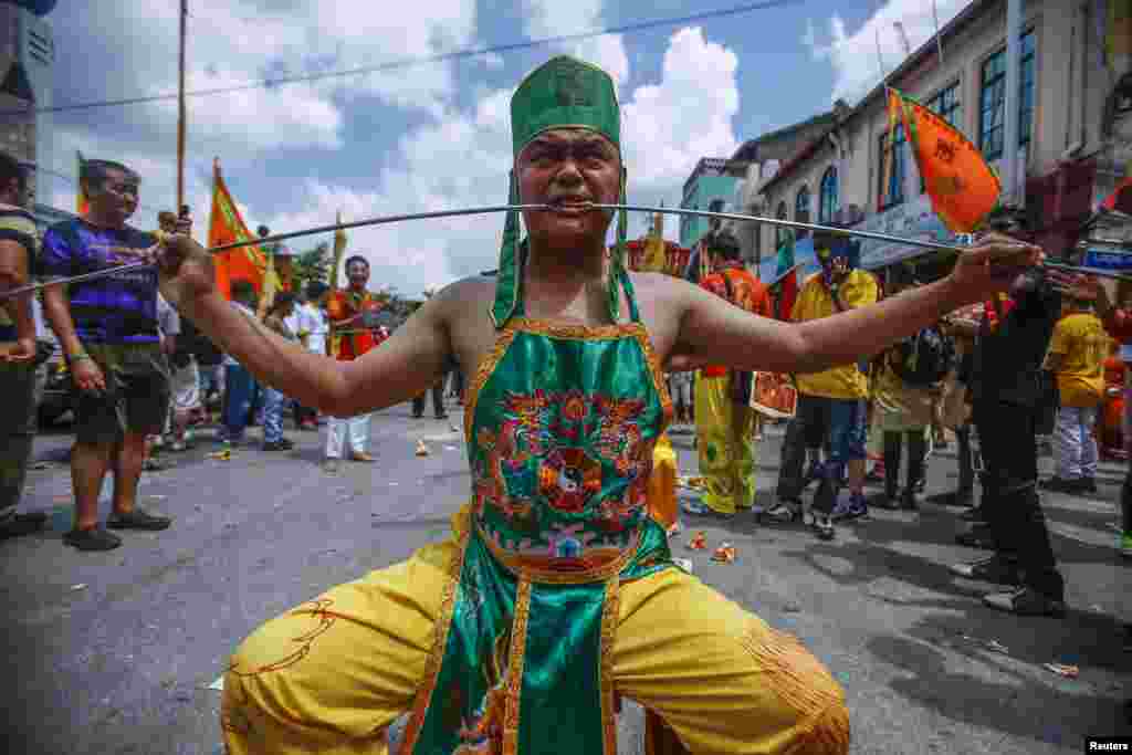 A Chinese devotee, who has his cheeks pierced with a skewer, sits on a chair before marching around Chinatown during the Guan Ping Festival in Kuala Lumpur, Malaysia. The festival, held in celebration to mark the birthday of Chinese deity Guan Ping, is believed to bring prosperity for local businesses.