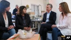 Argentina's President Mauricio Macri, Buenos Aires province governor Maria Eugenia Vidal, right, and Argentina's Minister of Social Development Carolina Stanley, left, talk to Lucila Godoy, president of the Osito Feliz textile factory, Sept. 18, 2017.