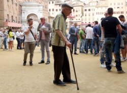 FILE - An elderly man walks in the old city centre of Siena, Italy, June 30, 2017.