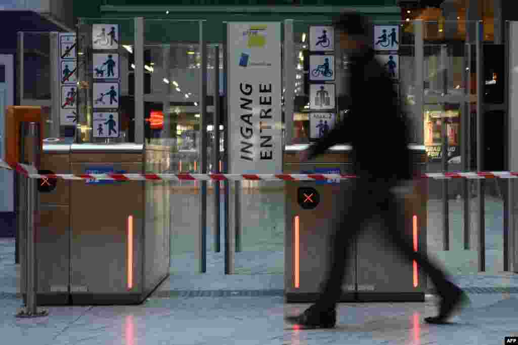 Seorang pria berjalan melewati pintu masuk sebuah stasiun kereta bawah tanah yang ditutup di Brussels. (AFP/Dirk Waem)