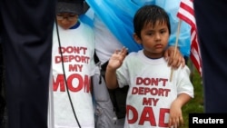 FILE - Boys wearing T-shirts calling for their parents not to be deported stand during a rally by immigration activists in Washington, D.C., Aug. 15, 2017. 