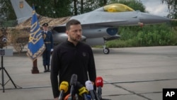 Presiden Ukraina Volodymyr Zelenskyy menjawab pertanyaan media sambil berdiri di depan jet tempur F-16 Angkatan Udara Ukraina di lokasi yang dirahasiakan di Ukraina, Minggu, 4 Agustus 2024. (Foto: AP)