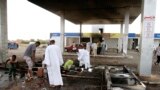 FILE - Men pick through debris after rioters torched a fuel station in Khartoum, Sudan.