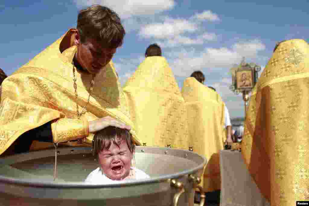 A priest baptizes a child at Novopyatigorsk lake near the Russian southern town of Pyatigorsk.