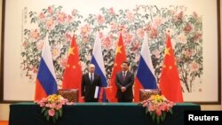 Presiden Rusia Vladimir Putin (kiri) dan Presiden China Xi Jinping saat menandatangani perjanjian kerjasama energi kedua negara di sela KTT APEC di Beijing, Minggu (9/11).