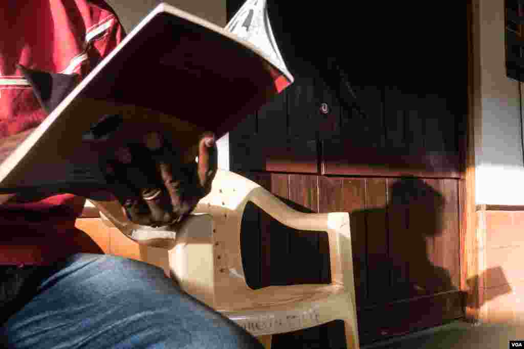 A poet and member of the Guinea-Bissau Writers Association, Rui Jorge Semedo, reads a passage from his book as he poses for a portrait, in Bissau, Guinea Bissau. (R. Shyrock/VOA)