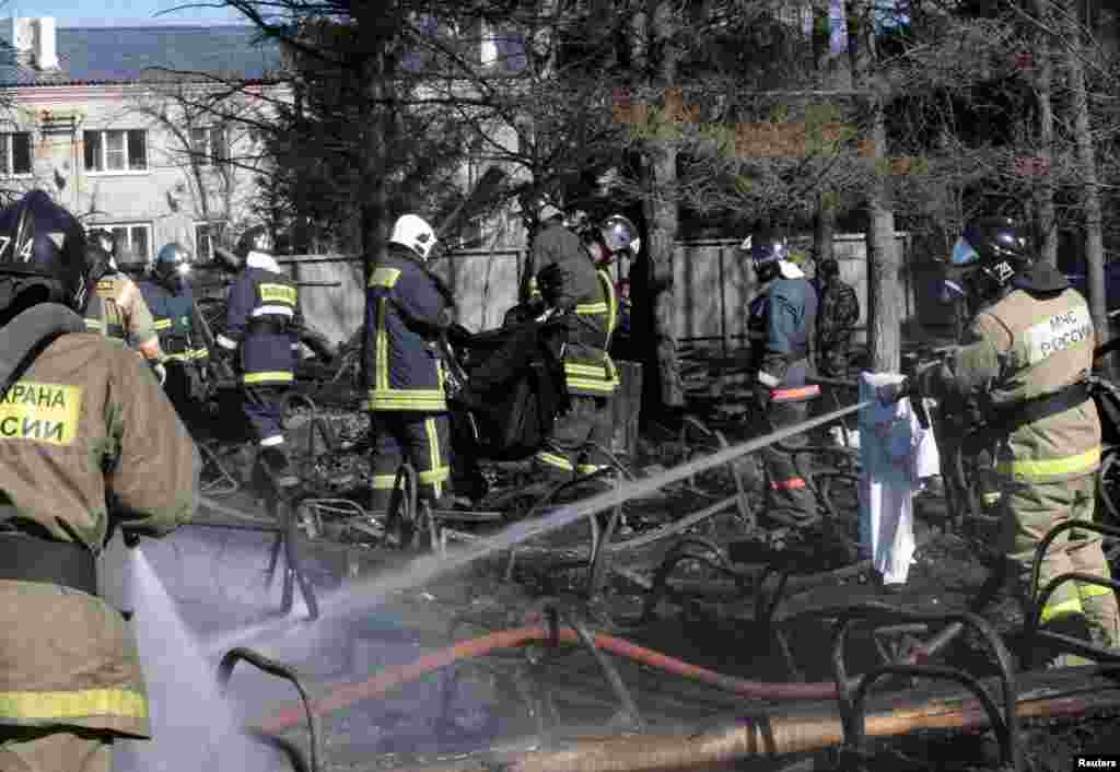 Russian emergency service staff spray water and remove remains at the site of a fire at a psychiatric hospital in the village of Ramensky, north of Moscow, April 26, 2013. 