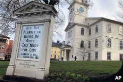 In this March 24, 2020, photo, a man walks past the First Baptist Church in America in Providence, R.I.
