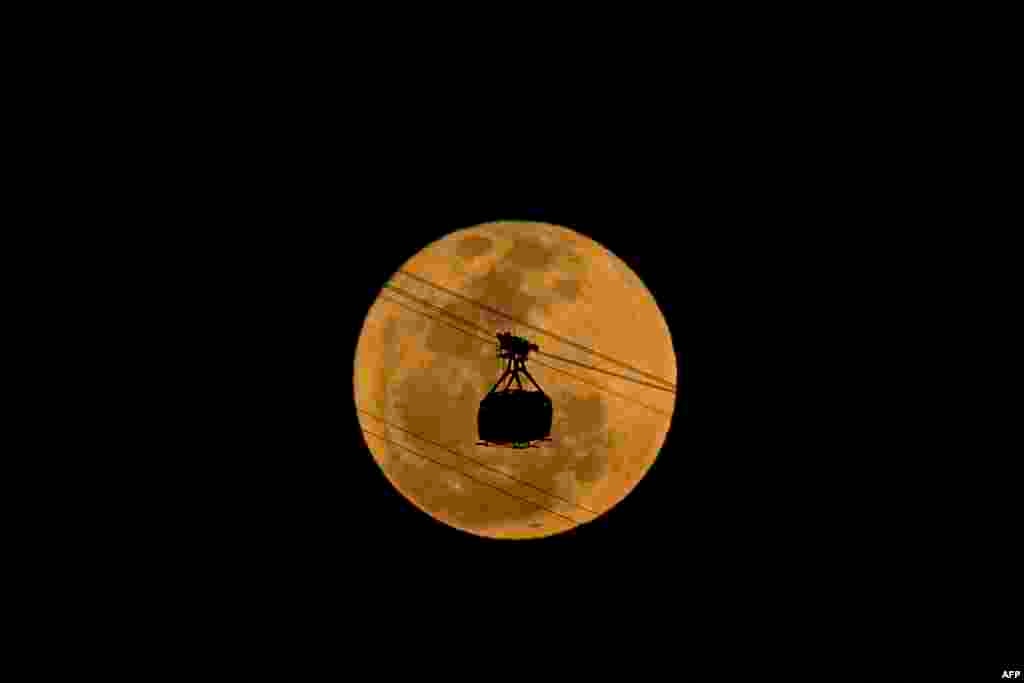 The moon rises behind the cable car of the Sugarloaf Mountain in Rio de Janeiro, Brazil, on Aug. 19, 2024.