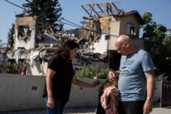 A young girl is comforted by her father next to a house damaged by a rocket fired from the Gaza Strip, in Yehod, central Israel, Wednesday, May 12, 2021.