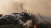 Firefighters spray water to extinguish a fire approaching to a settlement near Cokertme village in Bodrum region, Turkey, August 3, 2021.