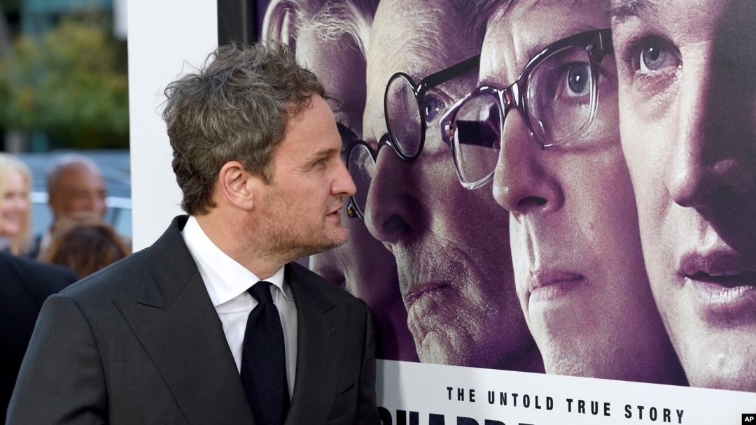 FILE - Jason Clarke looks at a movie poster as he arrives at the premiere of "Chappaquiddick" at the Samuel Goldwyn Theater, March 28, 2018, in Beverly Hills, California. 