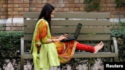 FILE - A student works on her computer sitting on a bench at Shaheed Benazir Bhutto Women's University in Peshawar, Pakistan, Oct. 19, 2017. 