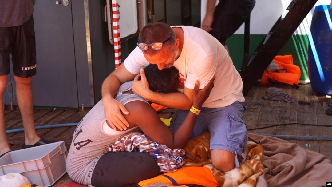 Seorang migran dihibur oleh awak kapal kemanusiaan Spanyol Open Arms di lepas pantai Pulau Sisilia Lampedusa, Italia selatan, 18 Agustus 2019. (Foto: AP)