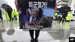 FILE - A protester holds a banner showing an image of U.S. President Donald Trump during a rally to oppose the United States' policies against North Korea near U.S. Embassy in Seoul, South Korea, Oct. 7, 2019. 