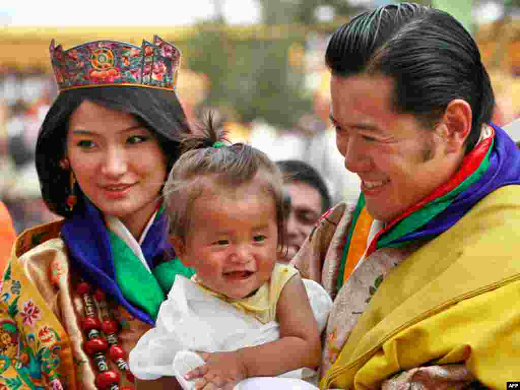 Quốc vương Jigme Khesar Namgyal Wangchuck, bên phải, bế một em bé trong lúc ngài chào mừng dân địa phương cùng với hoàng hậu Jetsun Pema trong một buổi lễ sau lễ cưới tại Punakha Dzong ở Punakha, Bhutan, vào thứ Năm 13 tháng 10 năm 2011. Quốc vương 31 tuổ