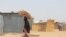 Une femme porte du bois sur la tête du camp informel de Yawuri à la périphérie de Maiduguri, capitale de l'État de Borno, le 29 mars 2021.