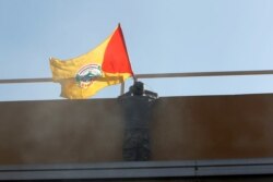 FILE - A flag of Shiite group Kataeb Sayyid al-Shuhada is placed on the wall of the U.S. Embassy during a protest, in Baghdad, Iraq, Dec. 31, 2019.