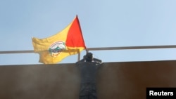 FILE - A flag of Shiite group Sayyid al-Shuhada is placed on the wall of the U.S. Embassy during a protest, in Baghdad, Iraq, Dec. 31, 2019.