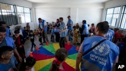 Niños palestinos desplazados por la ofensiva israelí en Gaza participan en una actividad organizada por activistas locales en una escuela administrada por la ONU en Jan Yunis, el 26 de junio de 2024. 