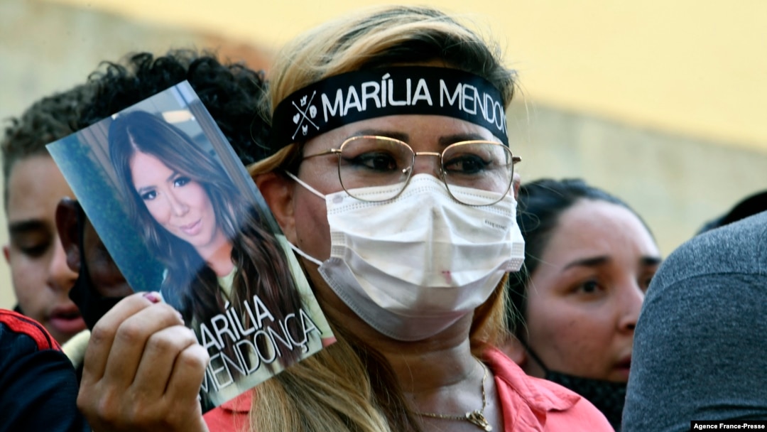 A fan of Brazilian singer Marilia Mendonca, 26, holds a picture of the late artist, outside the Arena Goiania sports center, in Goiania, state of Goias, Brazil, on Saturday, Nov. 6, 2021. 