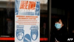 Seorang perempuan mengenakan masker saat berjalan melintas poster peringatan kesehatan di Hong Kong, China, 21 Januari 2020. (Foto: AFP)