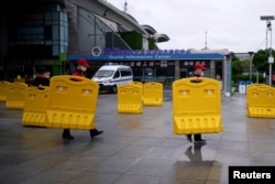 Staff members move barriers in front of a railway station of Wuhan on the first day of inbound train services resumed following the novel coronavirus disease (COVID-19) outbreak, in Wuhan, China, March 28, 2020.
