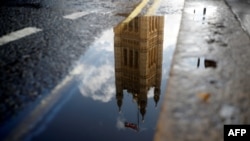 The Houses of Parliament are reflected in a puddle of rainwater in central London, Sept. 24, 2019.