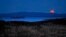 The nearly-full moon sets at dawn behind the Camden Hills in this view looking west across Penobscot Bay, near Camden, Maine.