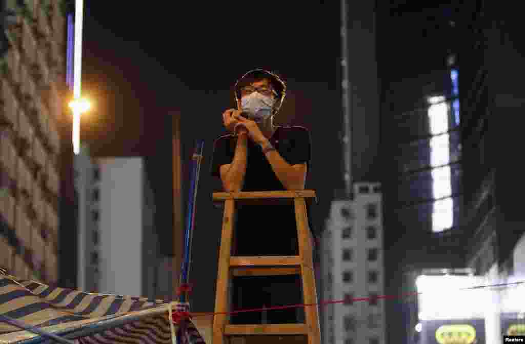 A student at a command post climbs on a ladder while watching for any aggressive moves by riot police at Mongkok shopping district in Hong Kong October 5, 2014. 