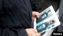 Seorang polisi Jerman memegang foto yang menampilkan foto tersangka teroris di depan terminal utama bandara Schoenefeld dekat Berlin (9/10).