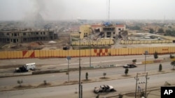 An empty street shows burned vehicles and damaged buildings in Fallujah, 65 kilometers west of Baghdad, Iraq, Jan. 3, 2014.