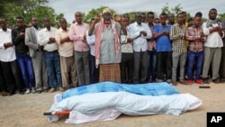 FILE - Mourners pray over the bodies of journalists Mohamed Abdikarim Moallim Adam, a reporter for London-based Universal Television, and Abdihakin Mohamed Omar, a producer for the Somali Broadcasting Corporation, at their funeral in Mogadishu, Somalia, July 27, 2015.