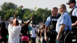 Policías observan una protesta en Ferguson, donde el Concejo de la ciudad se reune este martes por primera vez desde la muerte de Michael Brown.