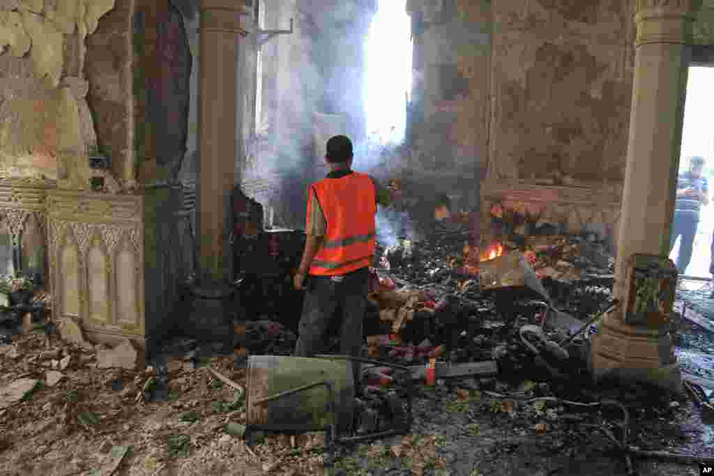 An Egyptian takes video of the burning remains of the Rabaah al-Adawiya mosque after Mosi supporters were cleared from the area by security forces, Nasr city, Cairo, August 15, 2013. 