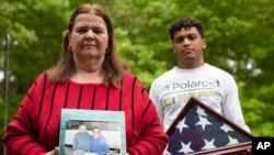 Florence Hopp holds a photograph of herself and her husband Robert Hopp during a cruise in 2017, as her son J.J. Brania-Hopp holds the American flag the military presented to them after his father's death, May 22, 2020,