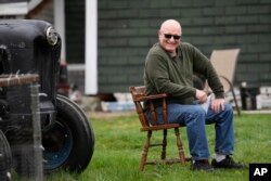 FILE - Charlie Robbins sits outside his home, Wednesday, April 26, 2023, in Columbia Falls, Maine. Robbins, an ardent sportsman, is opposed to a plan to build an enormous flagpole and theme park on undeveloped land cherished by hunters and fishermen. (AP Photo/Robert F. Bukaty)