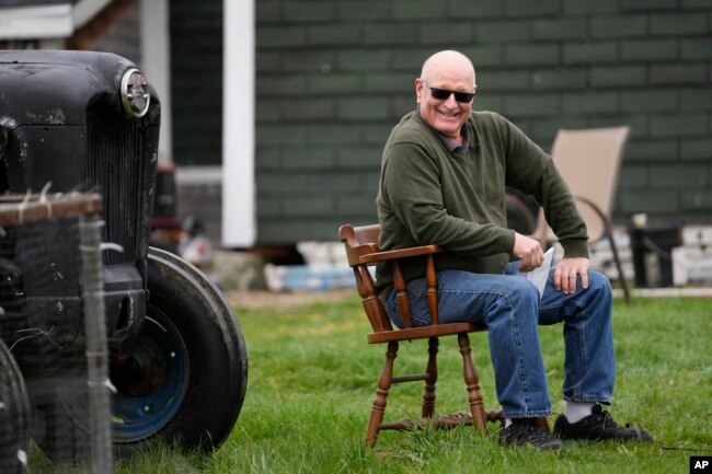 FILE - Charlie Robbins sits outside his home, Wednesday, April 26, 2023, in Columbia Falls, Maine. Robbins, an ardent sportsman, is opposed to a plan to build an enormous flagpole and theme park on undeveloped land cherished by hunters and fishermen. (AP Photo/Robert F. Bukaty)