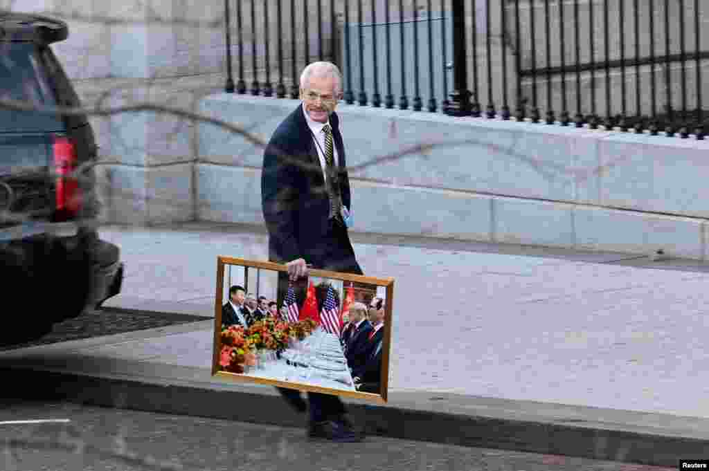 White House trade adviser Peter Navarro leaves the West Wing of the White House with a photograph of U.S. President Donald Trump and Chinese President Xi Jinping, in Washington, Jan. 13, 2021.